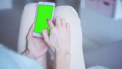 Beautiful girl using SmartPhone with pre keyed green screen sitting on sofa Stock Footage 73330662