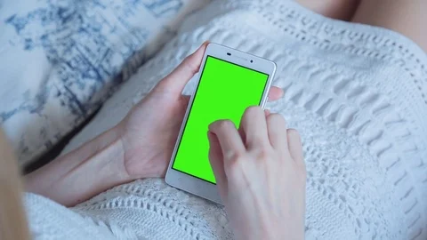 Beautiful girl using SmartPhone with pre-keyed green screen laying on sofa Stock Footage 73755174