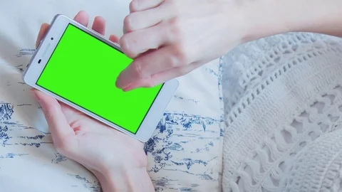 Beautiful girl using SmartPhone with pre-keyed green screen laying on sofa Stock Footage 73844444