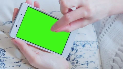 Beautiful girl using SmartPhone with pre-keyed green screen laying on sofa Stock Footage 73844559