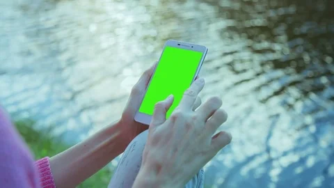 Beautiful Girl Using SmartPhone with pre-keyed green screen Sitting Near Lake 2 Stock Footage 74242817
