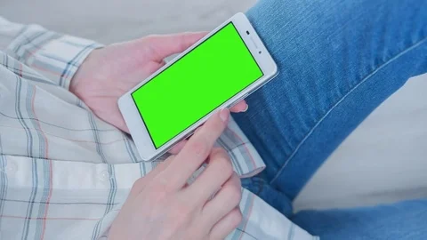 Beautiful Girl Using SmartPhone with Pre-Keyed Green Screen Sitting on the Floor Video stock 75552247