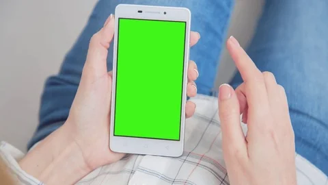 Beautiful girl using SmartPhone with pre-keyed green screen laying on sofa Video stock 79581276