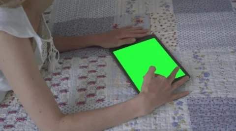 Beautiful girl using tablet pc with pre-keyed green screen lying on bed Stock Footage 63521928