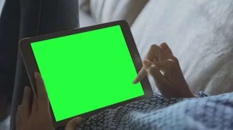Beautiful girl using tablet pc with pre-keyed green screen laying on sofa 2 Stock Footage 64693743
