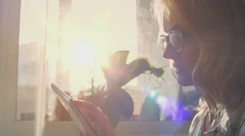 Beautiful girl using Tablet PC sitting on sofa near window 3 Stock Footage 65453824