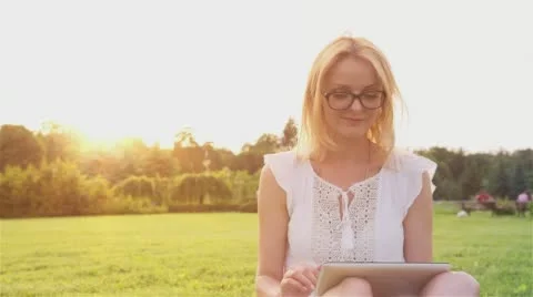 Beautiful Girl Using Tablet PC in the Park at Sunset 1 Stock Footage 66299239