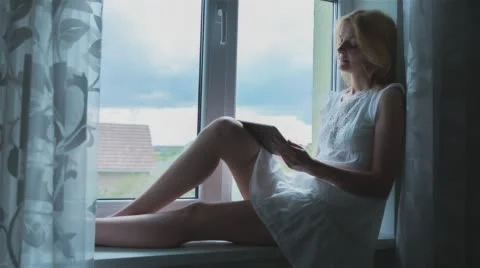 Beautiful Girl Using Tablet PC Sitting on Window Edge  Stock Footage 67076313