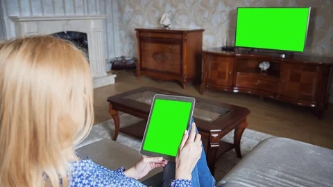 Beautiful girl using tablet pc with pre keyed green screen sitting on sofa Stock Footage 72520466