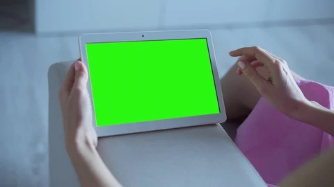 Beautiful girl using tablet pc with pre keyed green screen sitting on sofa Stock Footage 72520579
