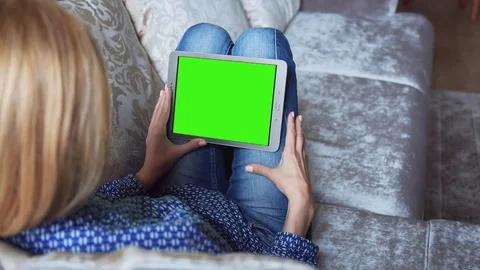 Beautiful girl using tablet pc with pre keyed green screen sitting on sofa Stock Footage 72522338