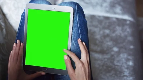 Beautiful girl using tablet pc with pre keyed green screen sitting on sofa Stock Footage 72522705