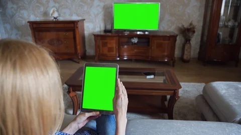 Beautiful girl using tablet pc with pre keyed green screen sitting on sofa Stock Footage 72523845