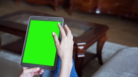 Beautiful girl using tablet pc with pre keyed green screen sitting on sofa Stock Footage 72525110