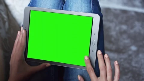 Beautiful girl using tablet pc with pre keyed green screen sitting on sofa Stock Footage 72531171