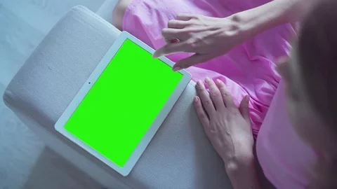 Beautiful girl using tablet pc with pre keyed green screen sitting on sofa Stock Footage 72785509