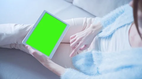 Beautiful Girl Using Tablet PC with Green Screen Laying on Sofa at Home 10 Stock Footage 73270267