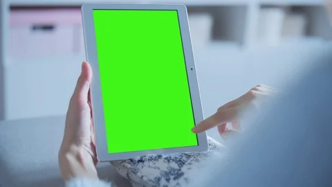Beautiful girl using tablet pc with pre keyed green screen sitting on sofa Stock Footage 73275219