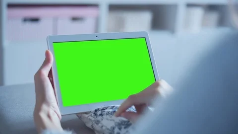 Beautiful girl using tablet pc with pre keyed green screen sitting on sofa Stock Footage 73275438