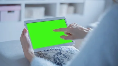 Beautiful girl using tablet pc with pre keyed green screen sitting on sofa Stock Footage 73307504