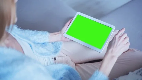 Beautiful girl using tablet pc with pre keyed green screen sitting on sofa Stock Footage 73327276