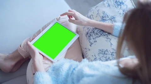 Beautiful girl using tablet pc with pre keyed green screen sitting on sofa Stock Footage 73373153