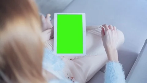 Beautiful girl using tablet pc with pre keyed green screen sitting on sofa Stock Footage 73393461