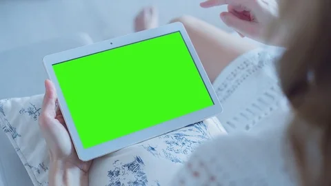 Beautiful girl using tablet pc with pre-keyed green screen sitting on sofa Stock Footage 73761462