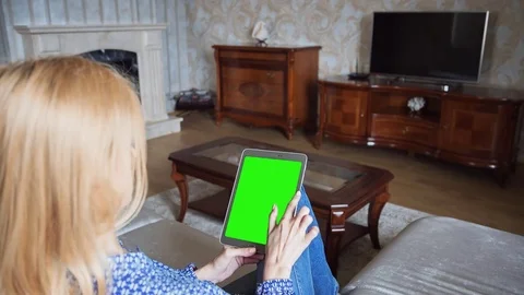 Beautiful girl using tablet pc with pre-keyed green screen sitting on sofa Stock Footage 74143858
