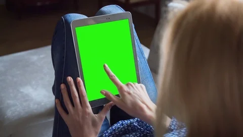 Beautiful girl using tablet pc with pre-keyed green screen sitting on sofa Stock Footage 74155003
