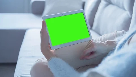 Beautiful Girl Using Tablet PC with Green Screen Laying on Sofa at Home 4 Stock Footage 74161528