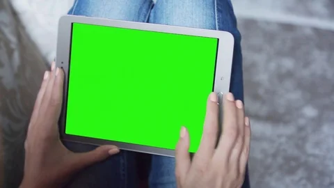 Beautiful girl using tablet pc with pre-keyed green screen sitting on sofa Stock Footage 74163621
