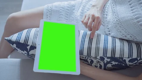 Beautiful girl using tablet pc with Pre-Keyed Green Screen sitting on sofa Stock Footage 74168334