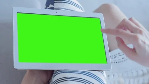 Beautiful girl using tablet pc with pre-keyed green screen sitting on sofa Stock Footage 74682406