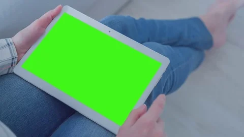 Beautiful girl using tablet pc with Pre-Keyed Green Screen sitting on sofa Stock Footage 74905393