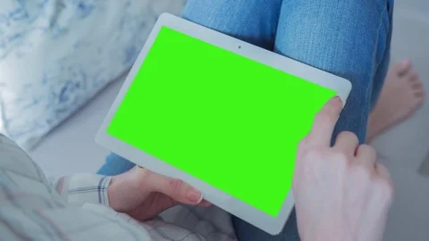 Beautiful girl using tablet pc with Pre-Keyed Green Screen sitting on sofa Stock Footage 74906064