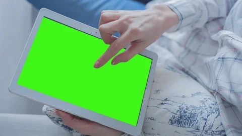 Beautiful girl using tablet pc with Pre-Keyed Green Screen sitting on sofa Stock Footage 74996979