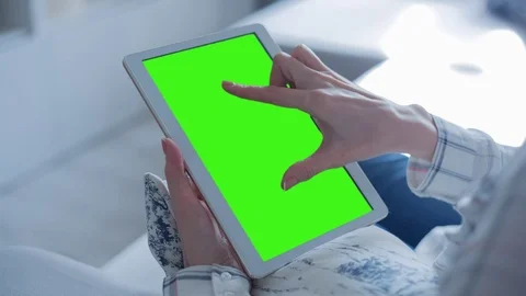 Beautiful girl using tablet pc with Pre-Keyed Green Screen sitting on sofa Video stock 75031950