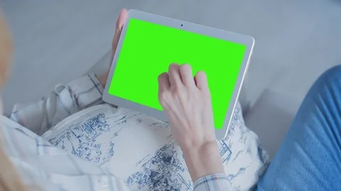 Beautiful girl using tablet pc with Pre-Keyed Green Screen sitting on sofa Video stock 75044721