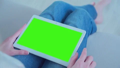 Beautiful girl using tablet pc with Pre-Keyed Green Screen sitting on sofa Video stock 75155104
