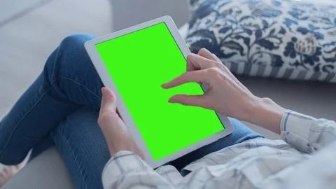 Beautiful girl using tablet pc with Pre-Keyed Green Screen sitting on sofa Stock Footage 75350026