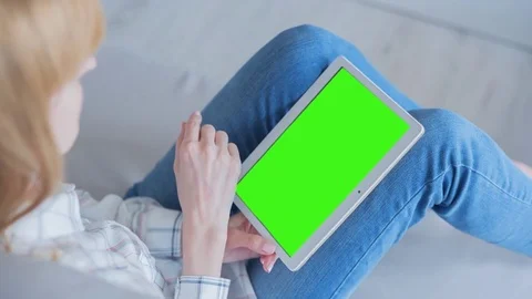 Beautiful girl using tablet pc with Pre-Keyed Green Screen sitting on sofa Stock Footage 75379135