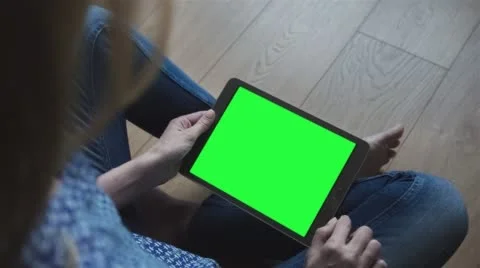 Beautiful girl using tablet with pre-keyed green screen sitting on the floor Stock Footage 64700481