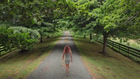 Beautiful girl walks down a Tree lined country road Stock Footage 147632675