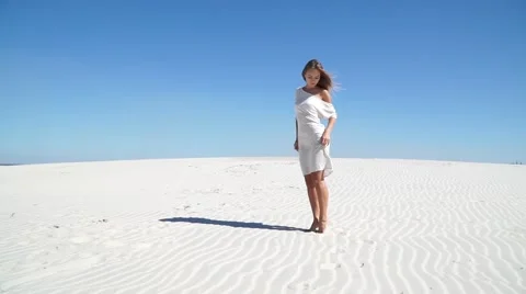 Beautiful girl in a white dress standing in the desert Stock Footage