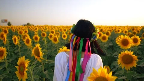 Beautiful girl with wreath running on yellow sunflower field, raising hands Stock Footage