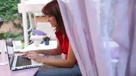 A beautiful girl is writing on his laptop in the garden. Stock Footage 59010154