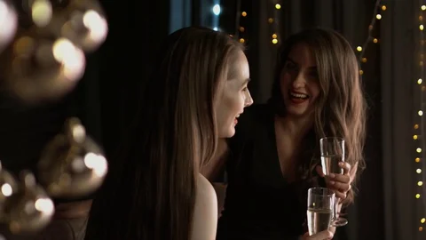 Beautiful girls with glasses of champagne emotionally speak in a Christmas Stock Footage