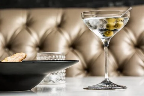 Beautiful glass of martini with olives accompanied by a gourmet dish. Stock Photos
