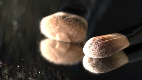 Beautiful glitter falling on the makeup brushes on the mirror on the black Stock Footage 75972405